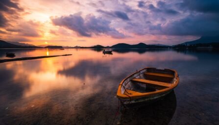 Beautiful shot of a small lake with a wooden rowboat in focus and breathtaking clouds in the sky